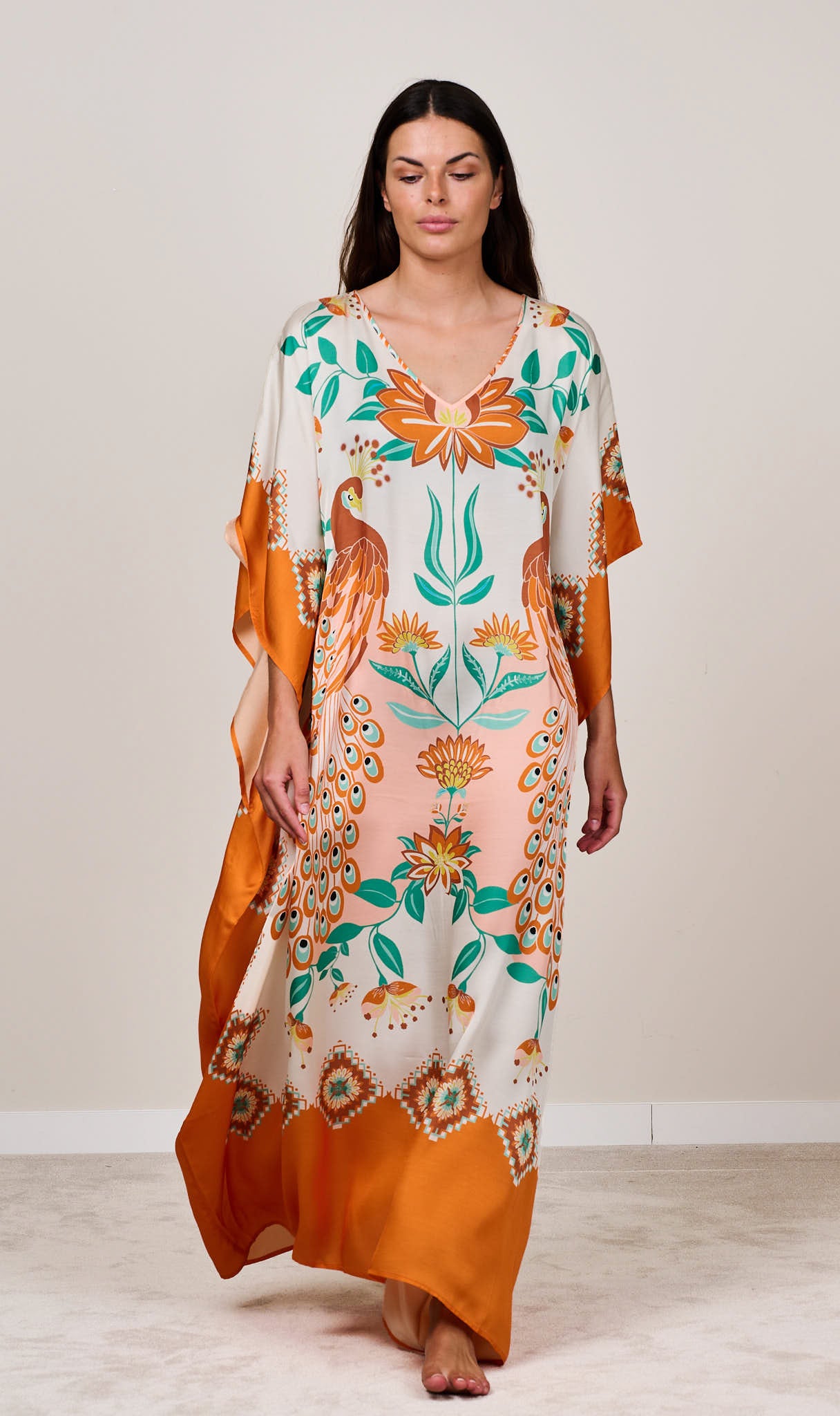 Orange and cream boho styled printed kaftan maxi dress with floral patterns. Styled on model for summer resort wear
