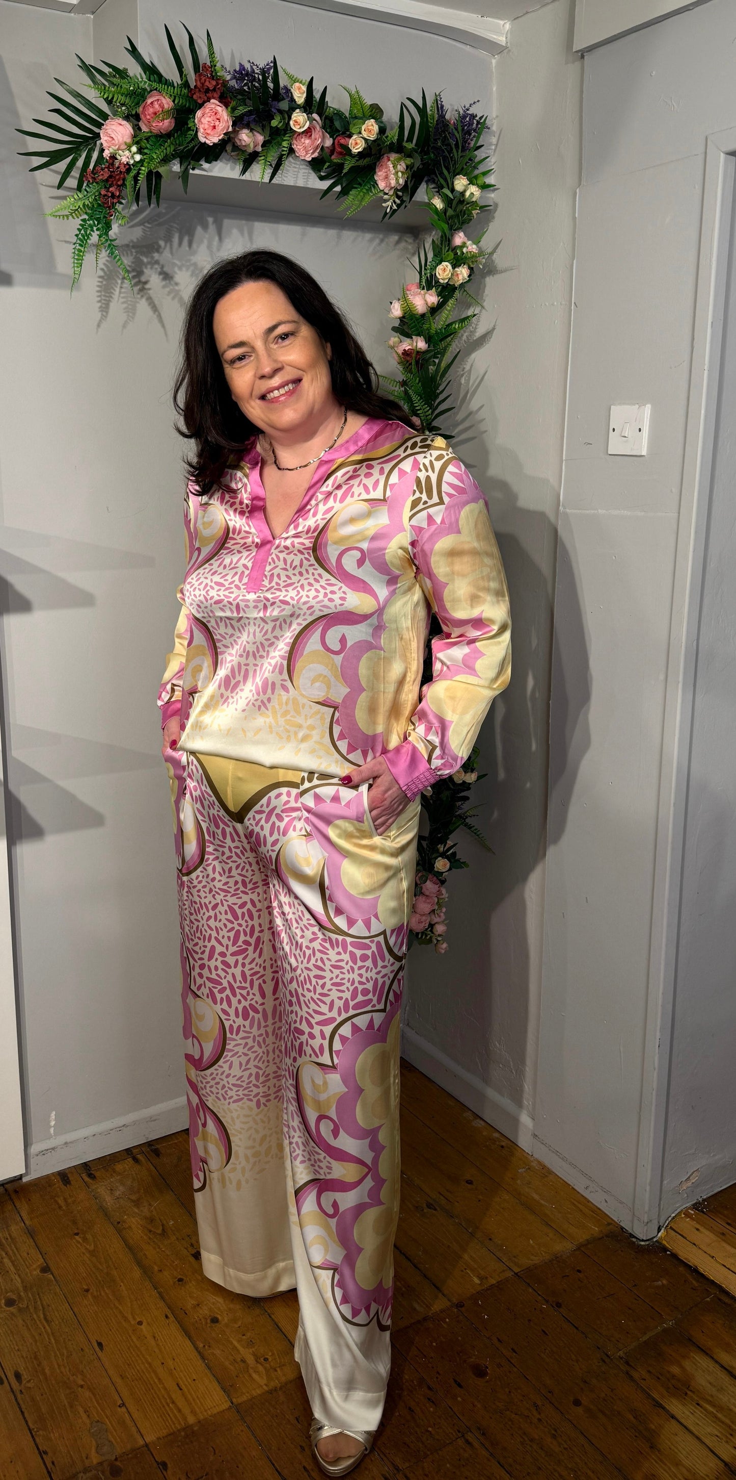 Wide-leg trousers with high waist and retro print in pink, yellow and cream tones, featuring side pockets and a soft draped fabric.