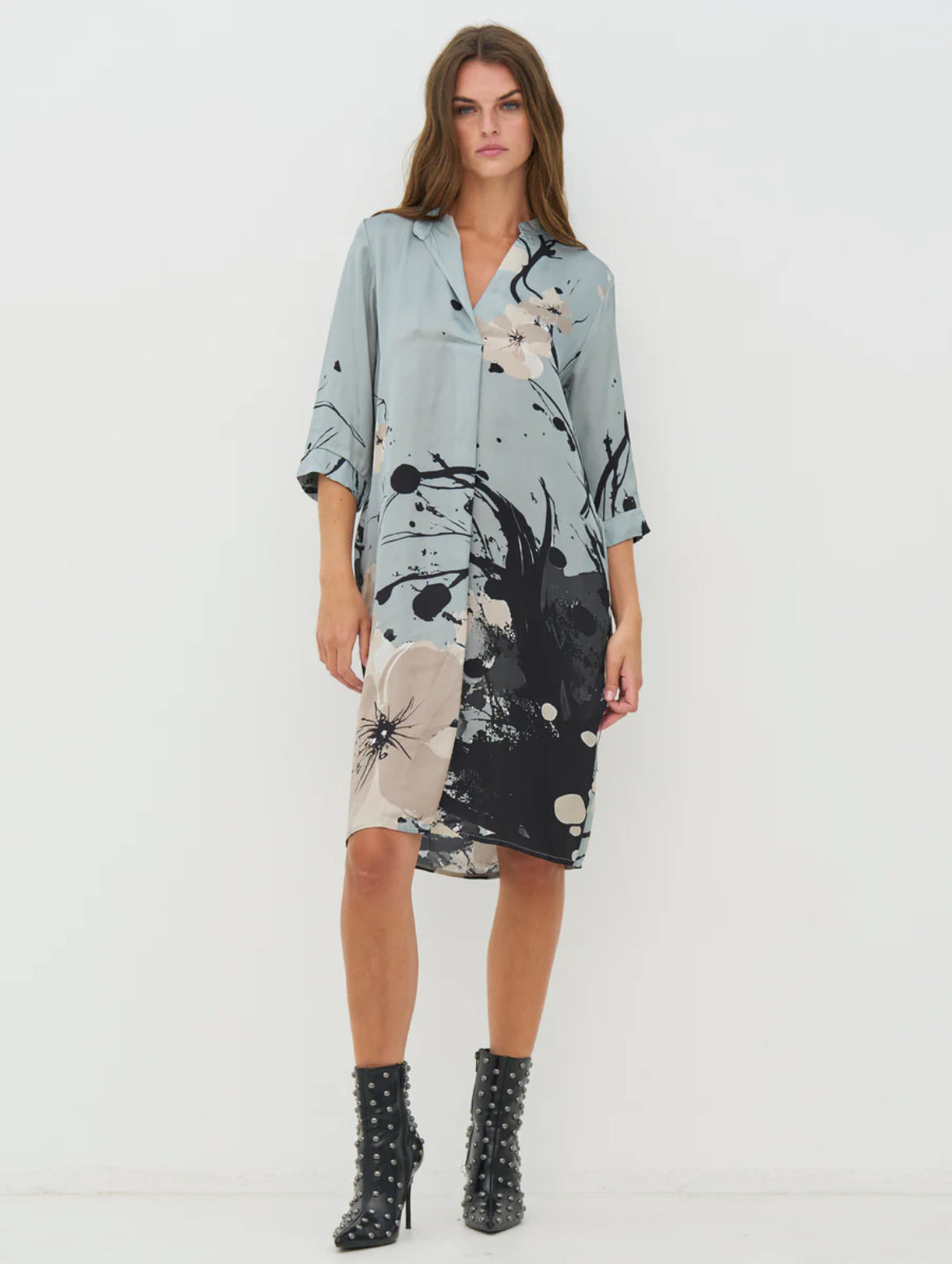 Woman wearing a floral dress with abstract patterns on a white background