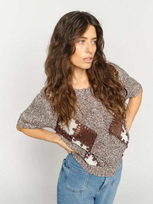 Woman wearing a patterned sweater and jeans on a plain background