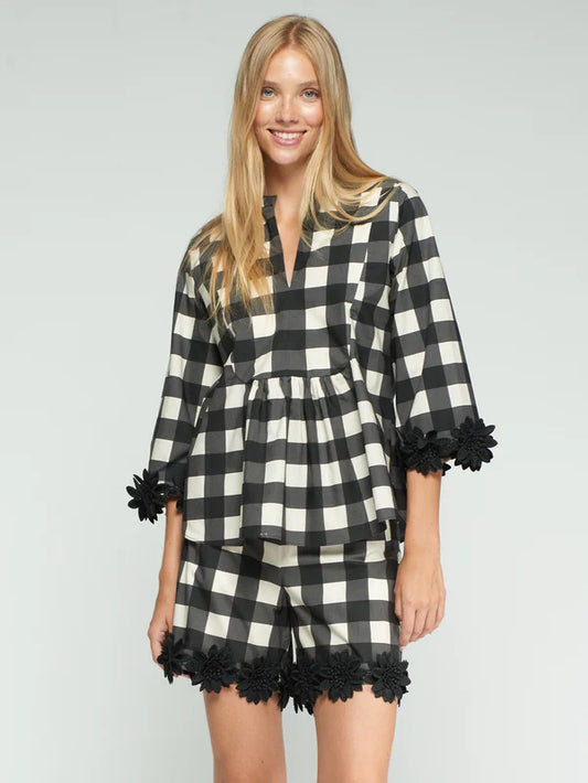 Woman wearing a black and white checkered dress with ruffled details on a gray background