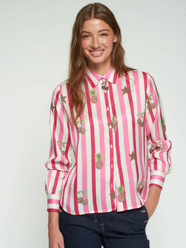 Woman wearing a pink and white striped shirt with pineapple patterns on a plain background