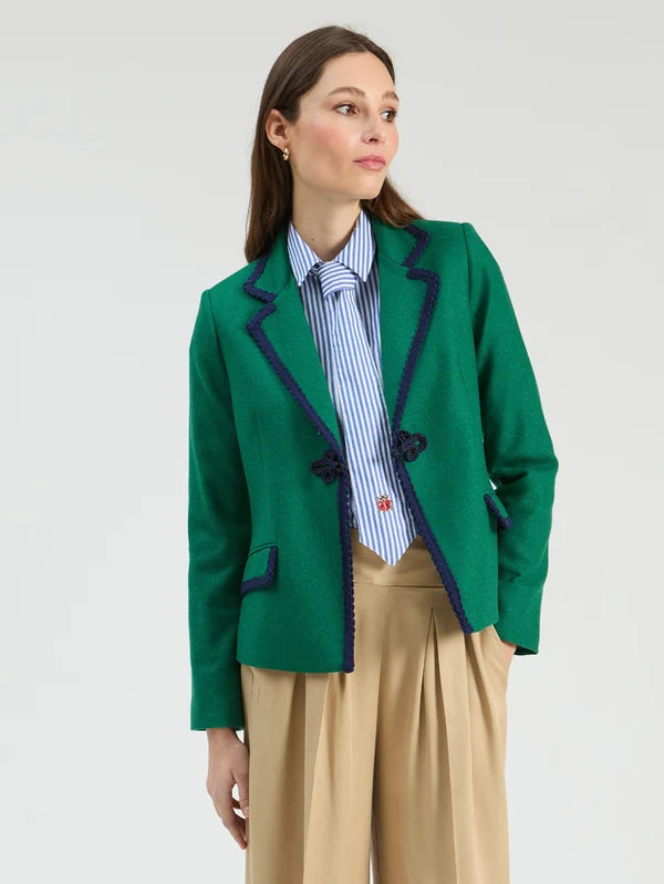 A woman wearing a bright green blazer with dark navy piping, 