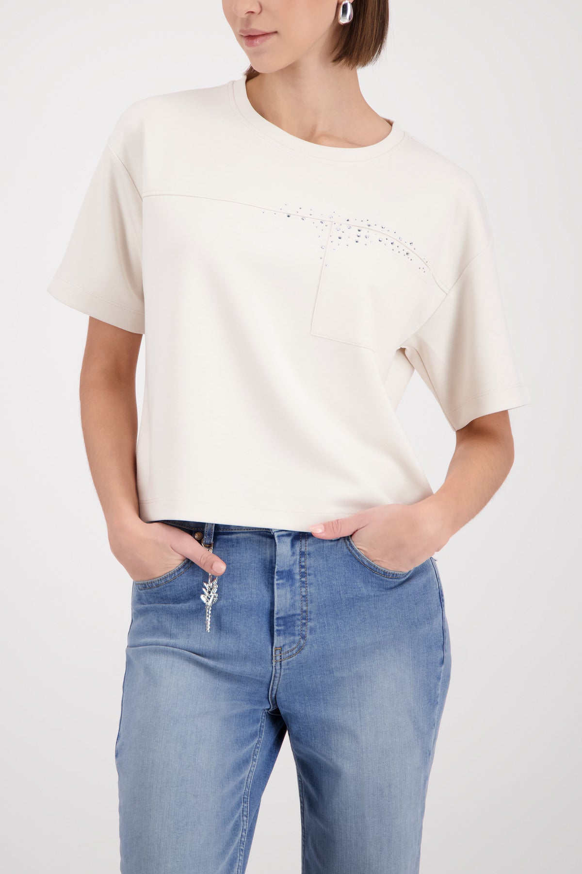 Person wearing a white oversized shirt and blue jeans on a white background