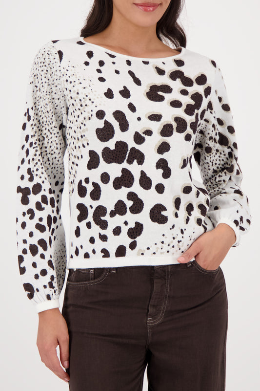Person wearing a white sweater with black leopard print pattern on a plain background