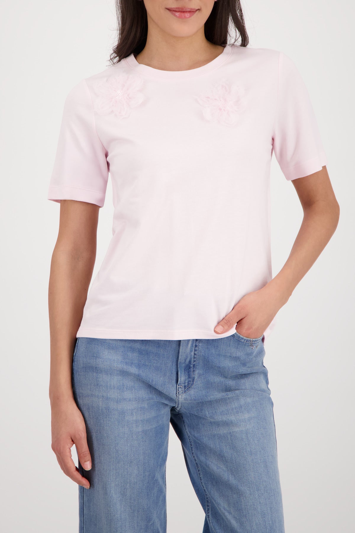 Person wearing a light pink t-shirt and blue jeans on a white background