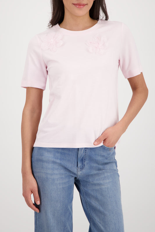 Person wearing a light pink t-shirt and blue jeans on a white background