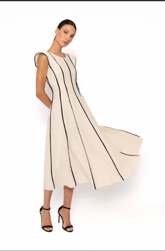 Woman wearing a beige dress with black trim on a white background