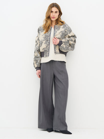 A woman modeling a cropped beige and gray floral patterned jacket with dark gray ribbed trim, from Nu Denmark