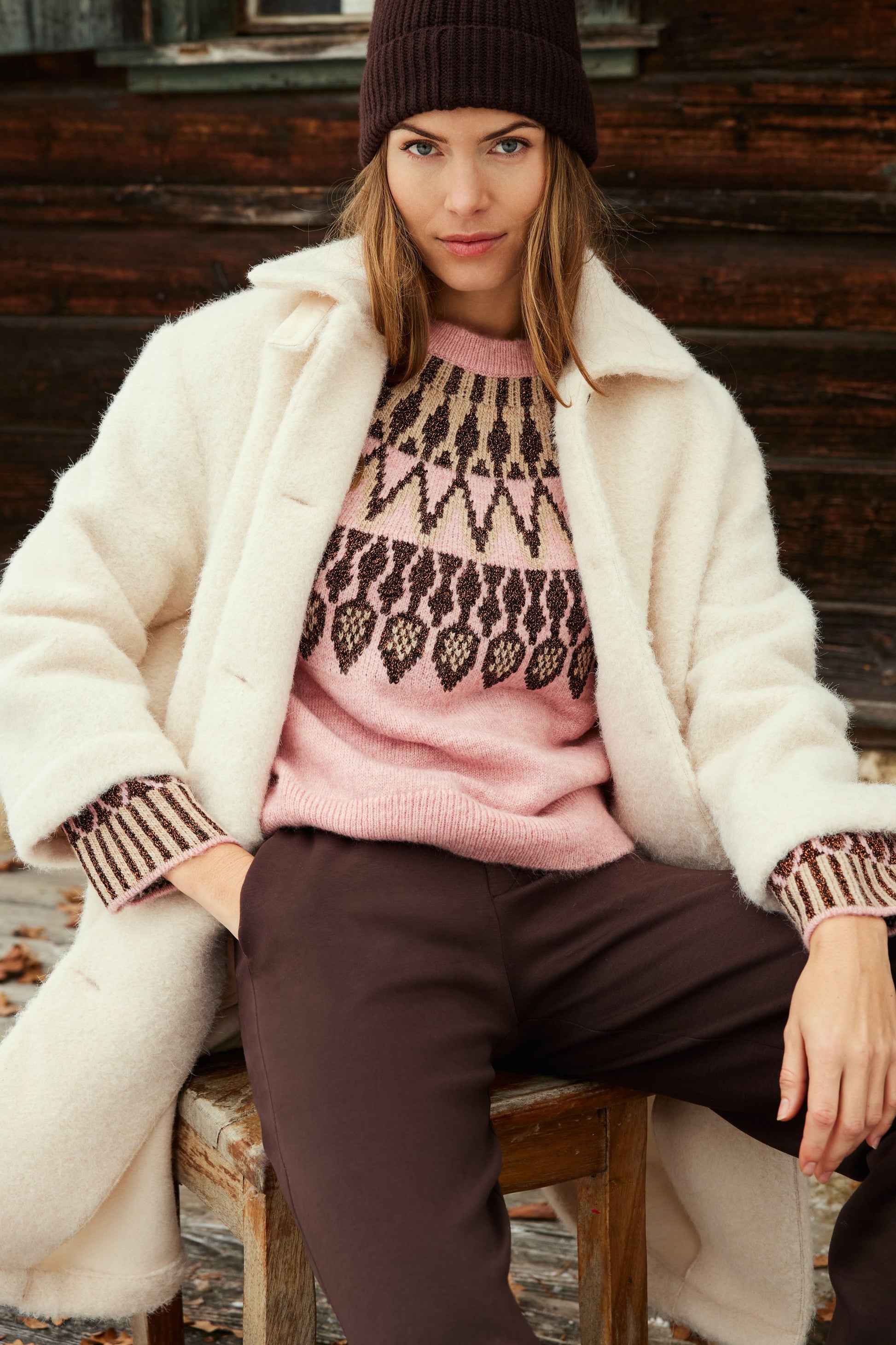 A pink knit sweater with a brown and beige geometric Fair Isle pattern across the yoke and cuffs,