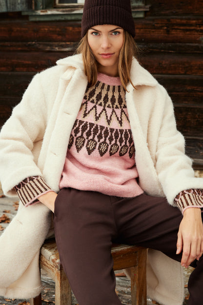 A pink knit sweater with a brown and beige geometric Fair Isle pattern across the yoke and cuffs,