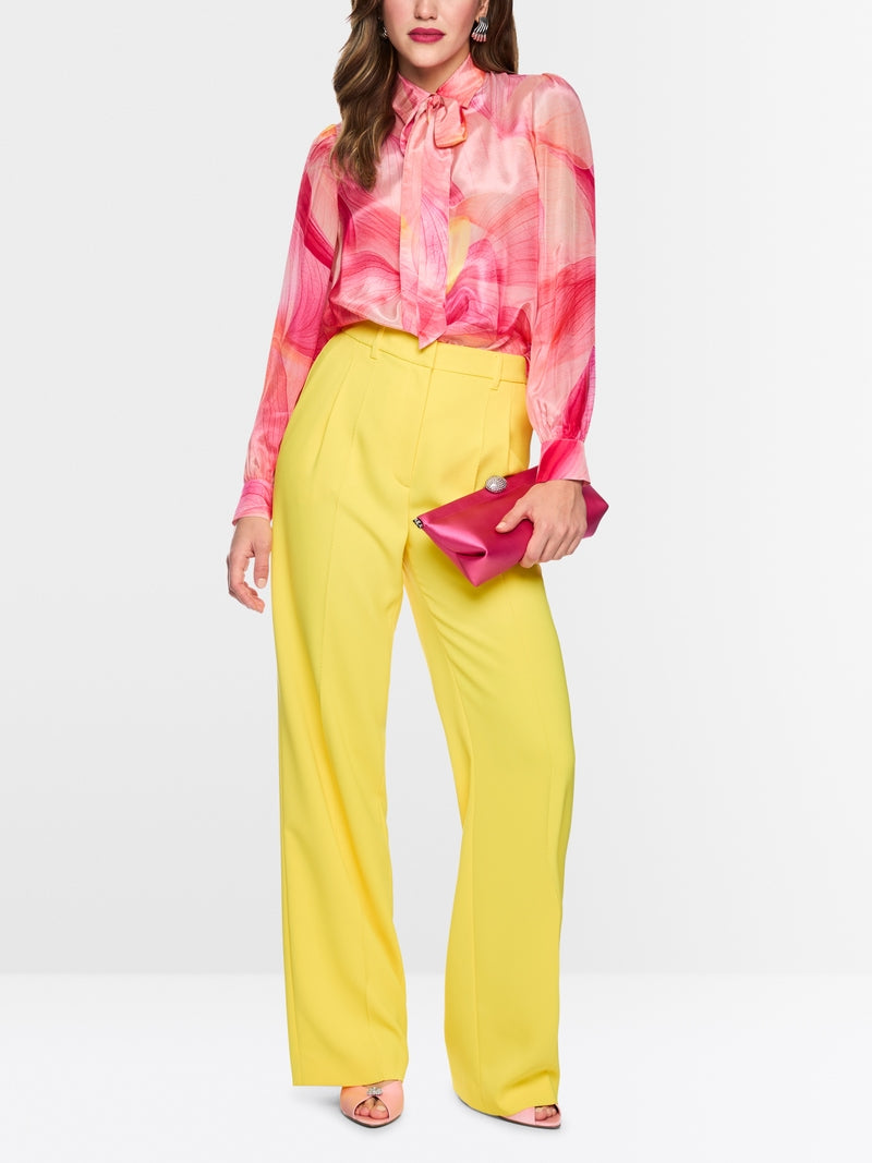 Woman wearing a pink blouse and yellow pants with a white background