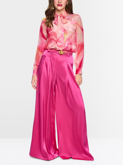 Woman wearing a pink floral blouse and pink wide-leg pants on a white background