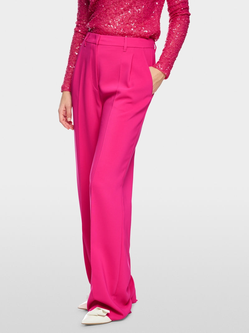 Person wearing a pink sequin top and matching pants on a light gray background