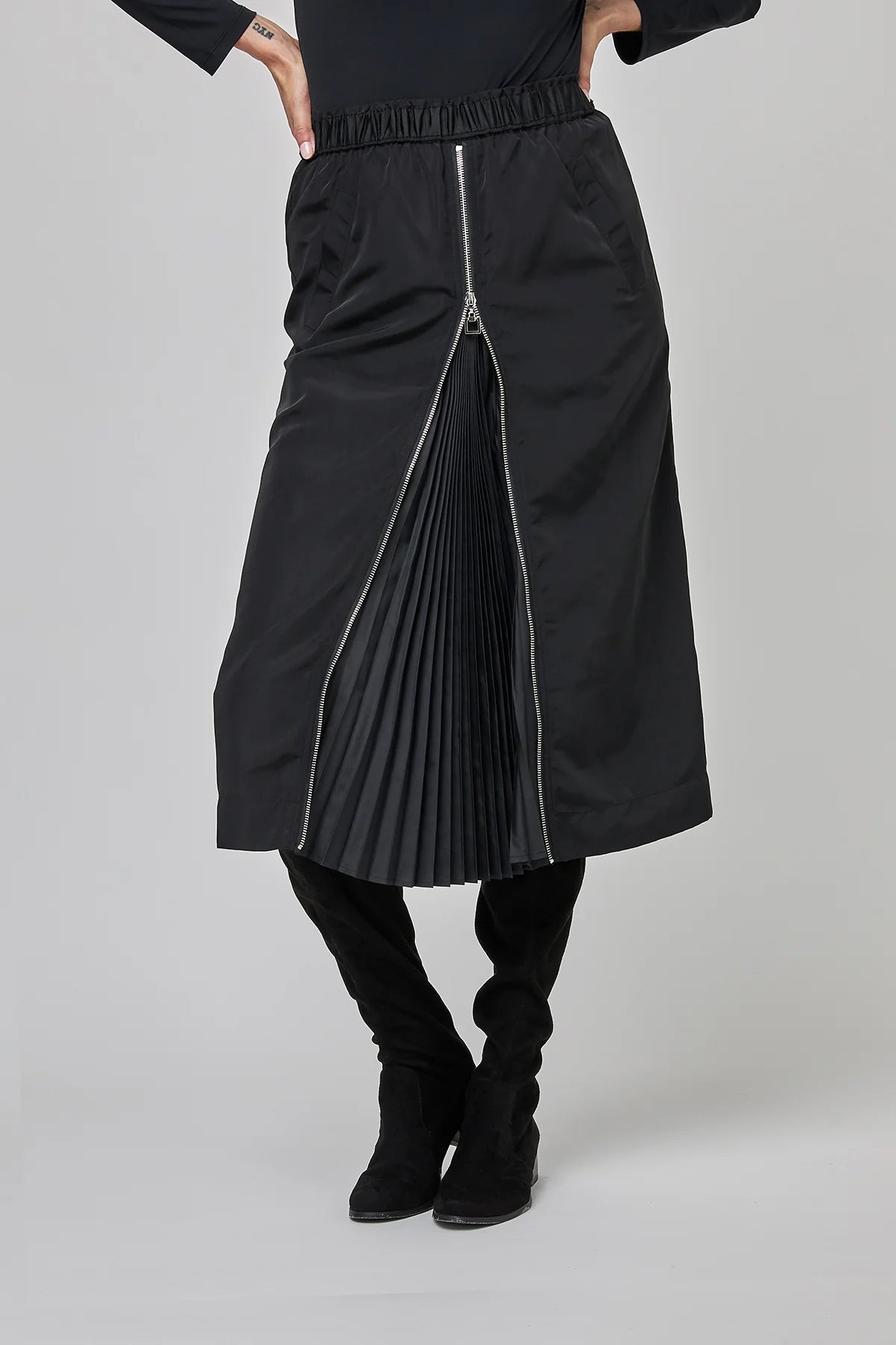 Person wearing a black pleated skirt with a zipper 