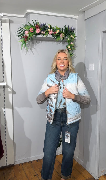 A woman modelling a light blue and white patterned quilted reversible gilet vest 