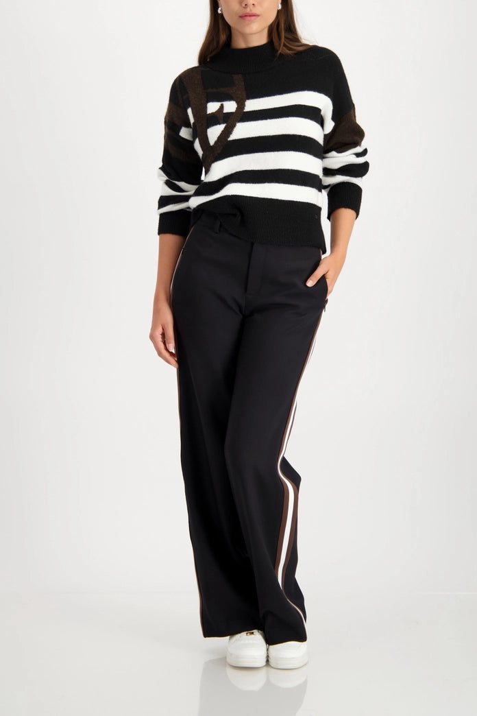 Woman wearing high-waisted black trousers with elastic material, vertical side stripes, straight fit 