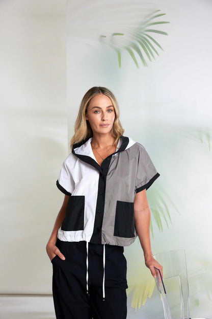 Woman wearing a black, white, and gray jacket with a blurred background