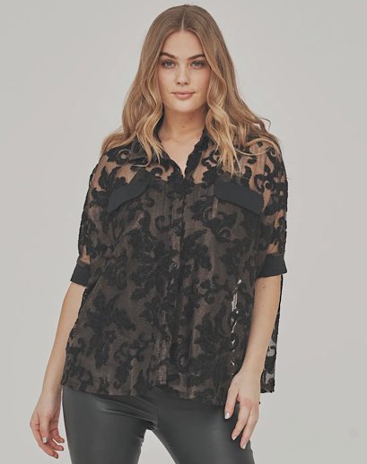 Woman wearing a brown lace blouse against a gray background