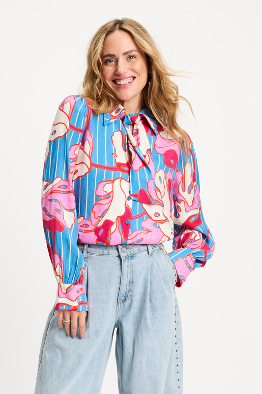 Woman wearing a colorful patterned blouse with a white background