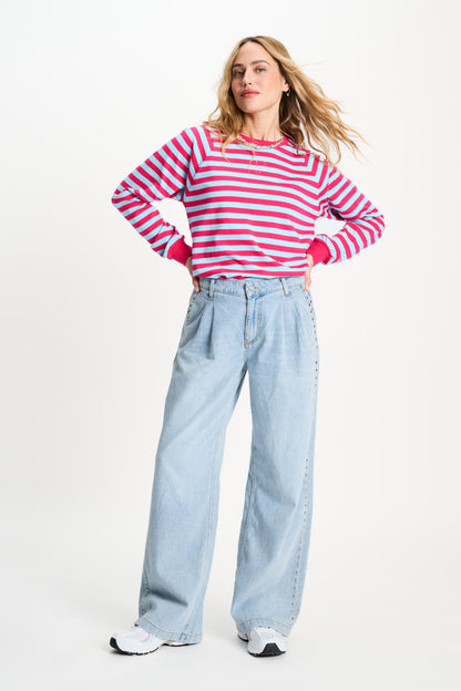 Woman wearing a red and white striped sweater and light blue jeans on a white background