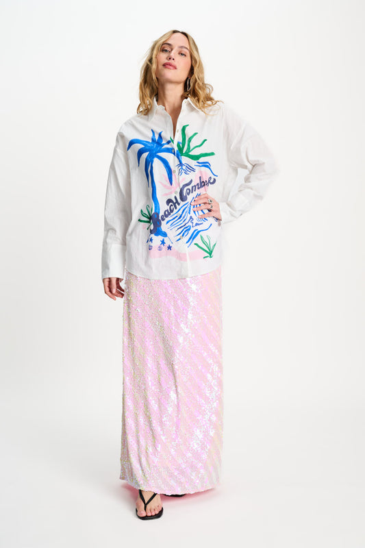 Woman wearing a white hoodie with colorful graphics and a pink skirt on a white background