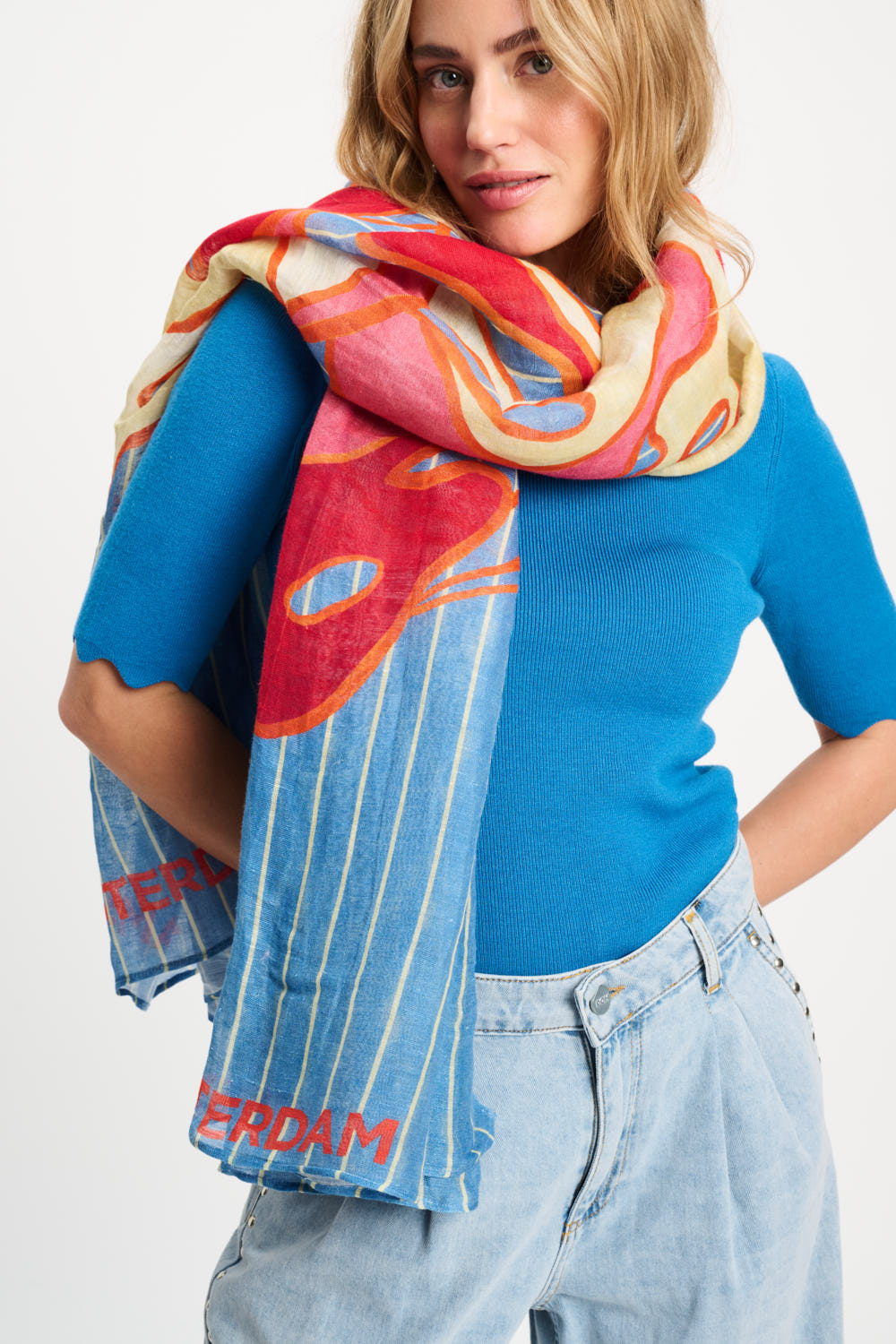 Woman wearing a colorful scarf with 'Amsterdam' text on a plain background