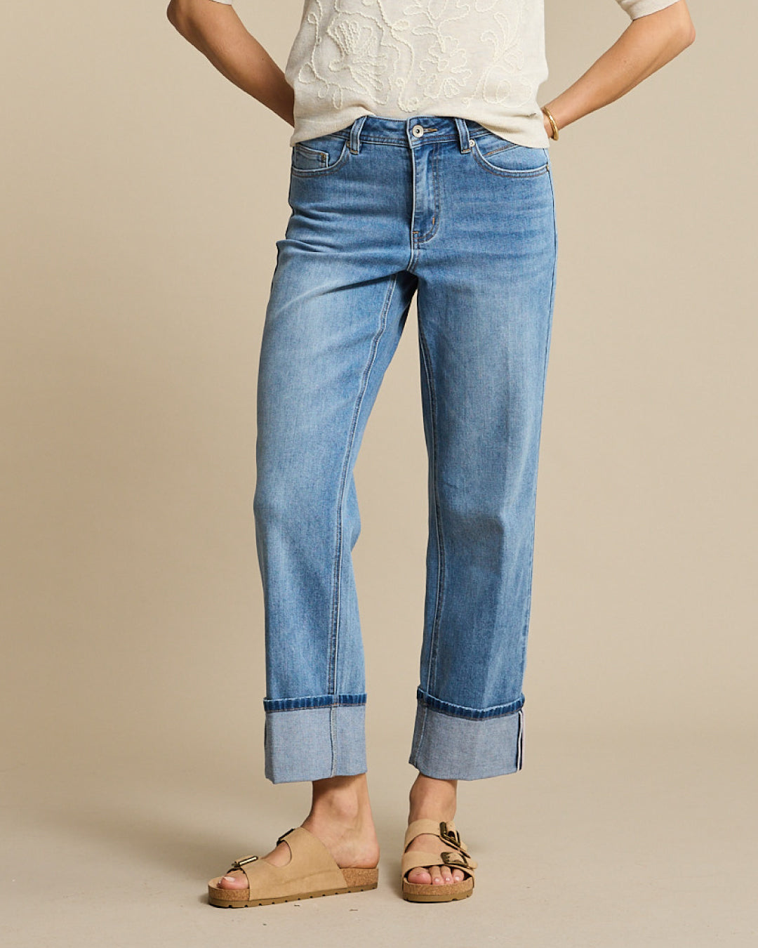Person wearing blue jeans with a beige background