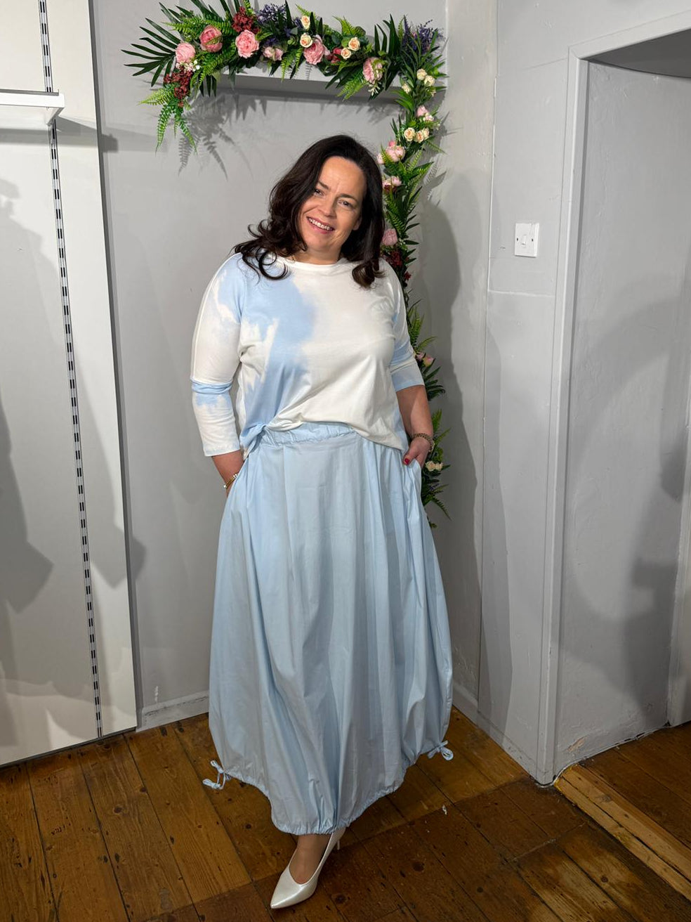 Powder blue balloon-style midi skirt with elasticated waistband and side pockets, paired with cream and blue top.
