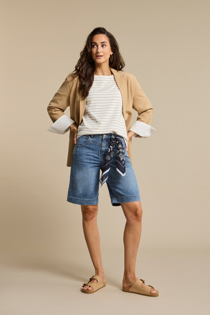 Model wearing mid-wash denim Bermuda shorts with a removable printed scarf tied at the waistband, 