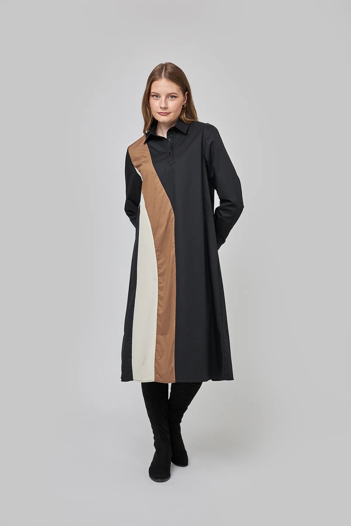 Model wearing a long-sleeve A-line shirt dress with diagonal camel and cream colorblock panels on a black 