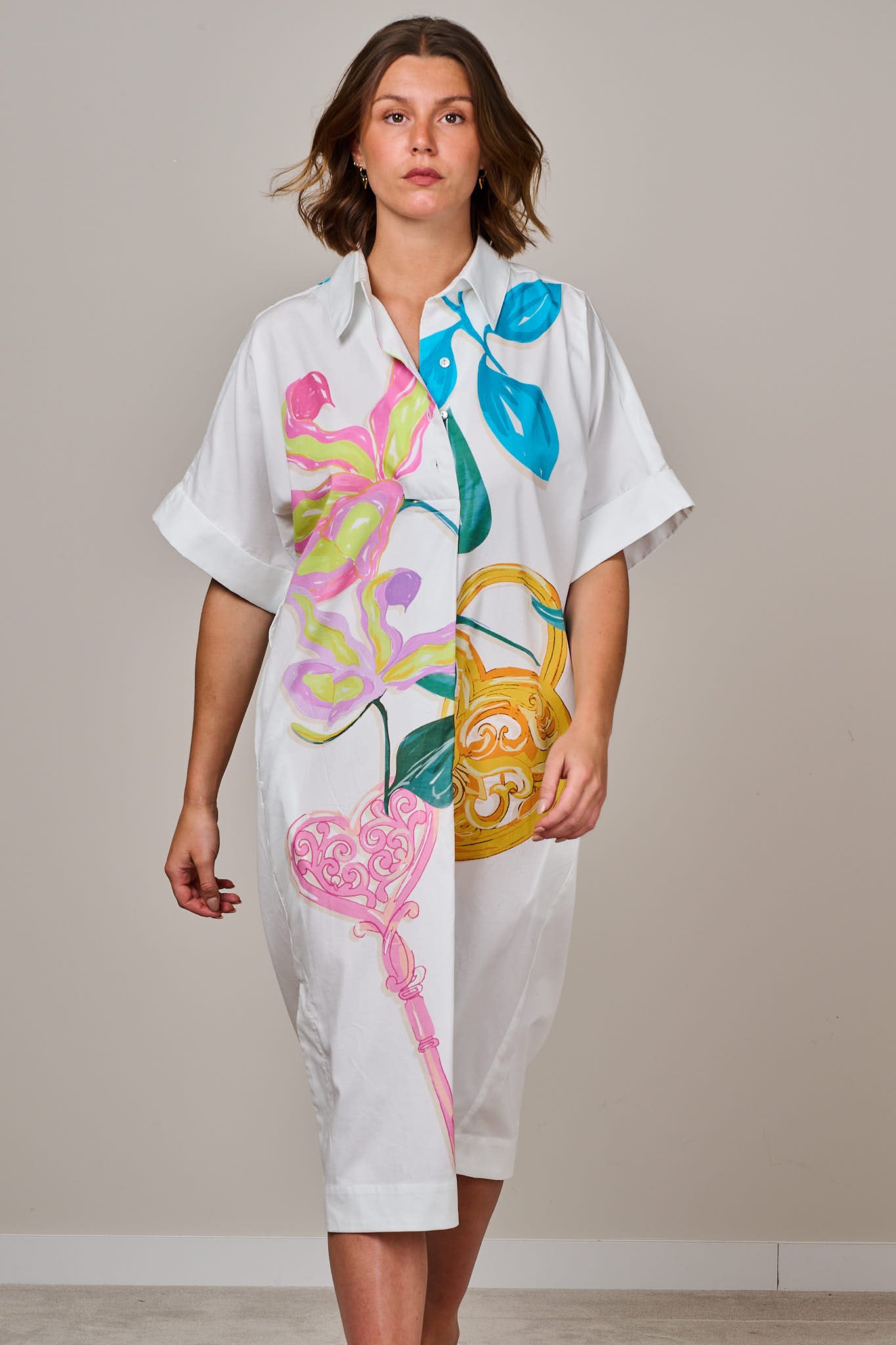 White printed midi shirt dress with colourful floral and ornamental design, short sleeves, button-down front, and relaxed fit, worn by a female model against a neutral background.