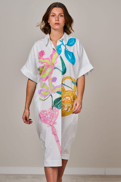 White printed midi shirt dress with colourful floral and ornamental design, short sleeves, button-down front, and relaxed fit, worn by a female model against a neutral background.