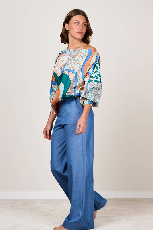 Woman wearing an abstract print boat neck top with three quarter length sleeves.